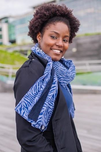 Smiling Woman Wearing Coat and Scarf Standing Near Building