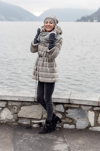 Smiling Woman Wearing Grey Hooded Coat Standing Beside Body Of Water