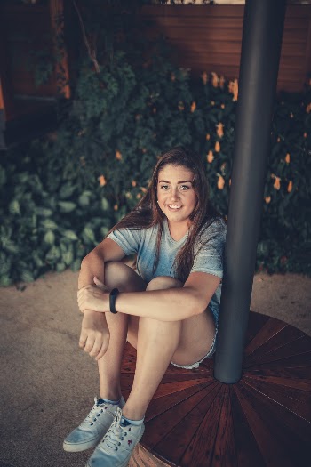 Smiling Woman Wearing Grey Shirt Sitting Beside Black Pole