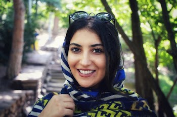 Smiling Woman Wearing Multicolored Headscarf and sunglasses Near Green Trees