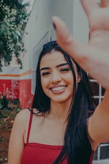 Smiling Woman Wearing Red Camisole Near Red and White Building