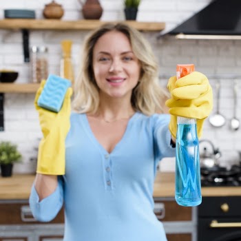 Smiling woman wearing rubber gloves holding detergent with sponge Free Photo