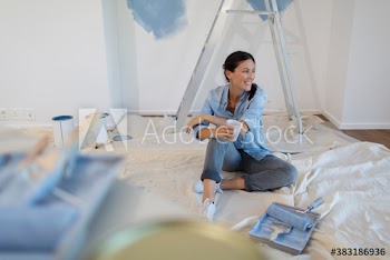 Smiling woman with coffee taking a break from painting room blue