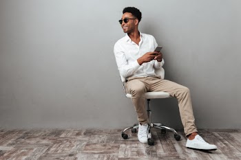 Smiling young african man sitting in a chair Free Photo