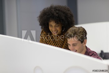 Smiling young business people working in office cubicle