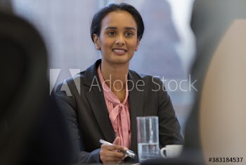 Smiling young businesswoman listening in conference room meeting
