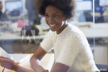 Smiling young businesswoman using digital tablet in office