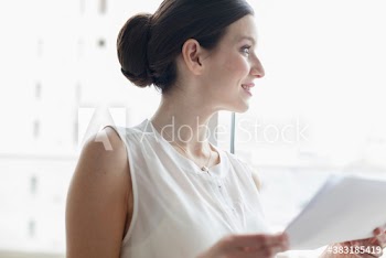 Smiling young corporate businesswoman in window