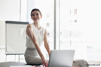 Smiling young corporate businesswoman using laptop in conference room