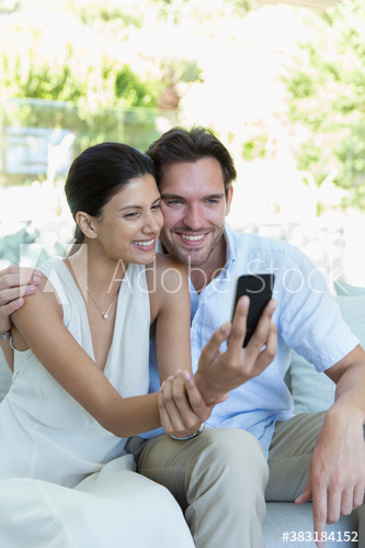 Smiling young couple taking selfie on patio