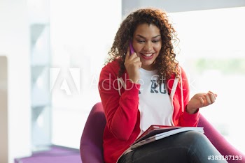 Smiling young female college student talking on smart phone