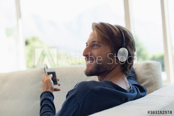 Smiling young man listening to music with headphones and mp3 player