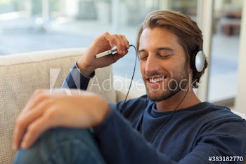Smiling young man listening to music with headphones and smart phone