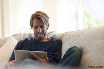 Smiling young man using digital tablet on sofa