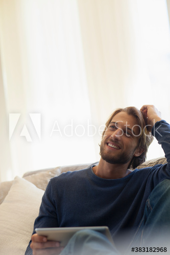 Smiling young man using digital tablet on sofa