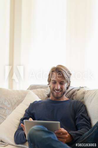 Smiling young man using digital tablet on sofa
