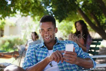 Smiling young man using smart phone in park