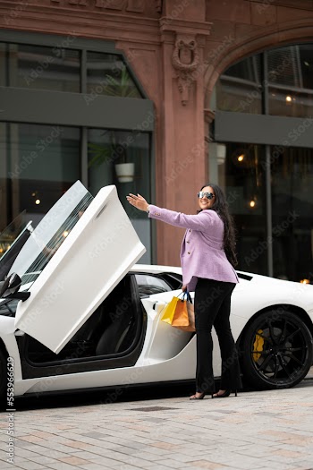 Smiling young woman getting in luxury car