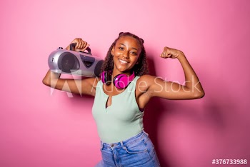 Smiling young woman holding stereo and showing biceps