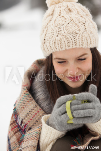 Smiling young woman in warm clothing enjoying hot coffee