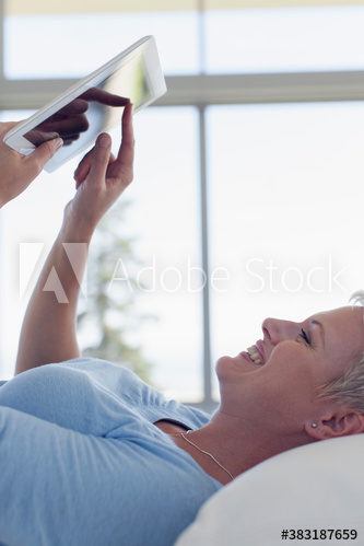 Smiling young woman laying and suing digital tablet