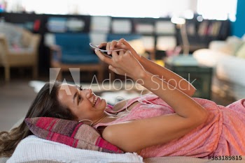 Smiling young woman listening to music on bed