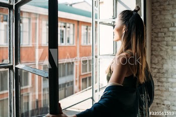 Smiling young woman opening window in morning