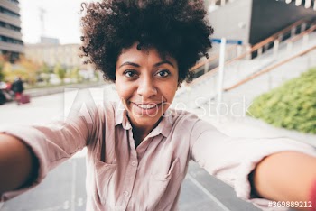 Smiling young woman taking selfie on street