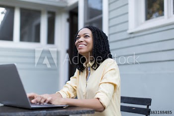 Smiling young woman using laptop on patio