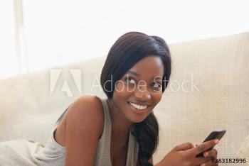Smiling young woman using smart phone on sofa
