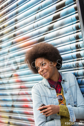 Smiling young woman with afro against graffiti wall