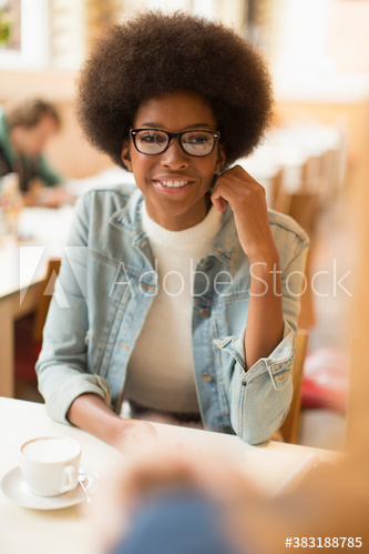 Smiling young woman with afro drinking cappuccino in cafe