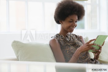 Smiling young woman with afro using digital tablet on sofa