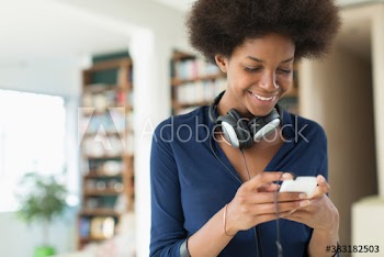 Smiling young woman with headphones texting with smart phone