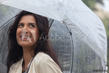 Smiling young woman with umbrella in rain
