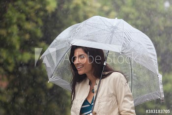 Smiling young woman with umbrella in rain