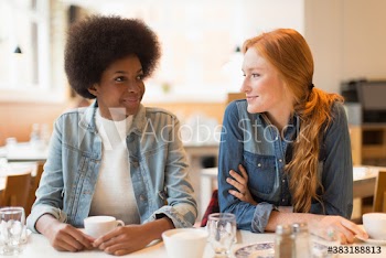 Smiling young women friends drinking coffee in cafe