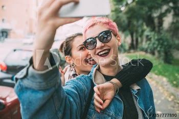 Smiling young women taking selfie with smartphone outdoors