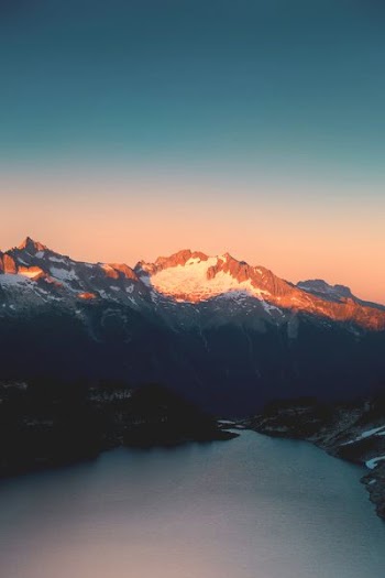 snow capped mountain near lake at daytime