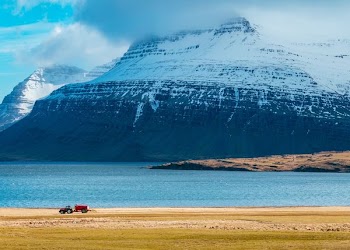 snow capped mountain next to body of water