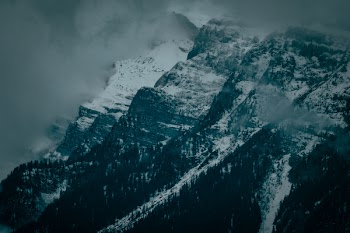 Snow Capped Mountain Range Under Cloudy Skies