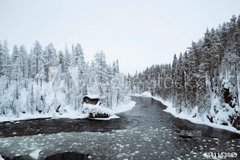 Snow-covered hut by  river in the Oulanka National Park, Finland
