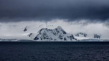 snow-covered mountain near body of water