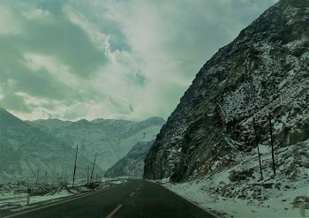 Snow Covered Mountain Ranges Near the Asphalt Road Under the Cloudy Sky