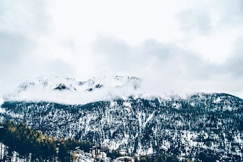 snow covered mountain under white clouds during daytime