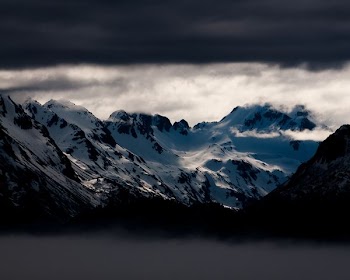 snow covered mountains under white clouds at daytime