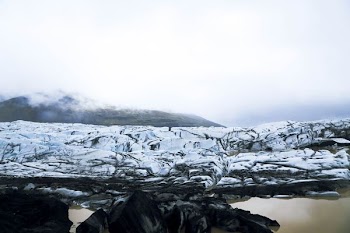 snow covered rocky field near body of water during daytime