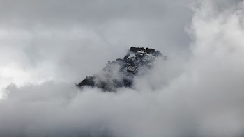 Snowy mountain summer peeks through clouds in Franz Josef Glacier