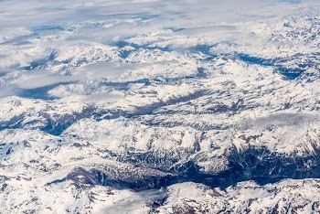 snowy mountains beside boy of water under blue sky during daytime
