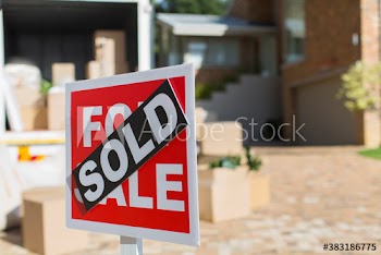 Sold sign outside house and moving van in driveway